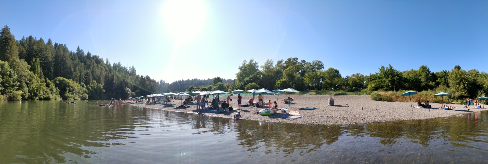 Wide summer panorama of the Russian River and crowds at Johnson's Beach, Guerneville