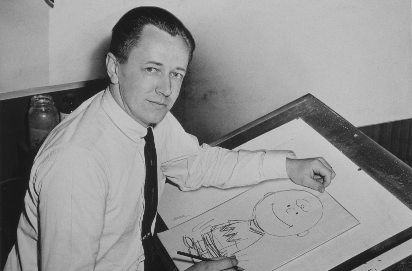 Charles Schulz at his drawing board in 1956, sketching Charlie Brown
