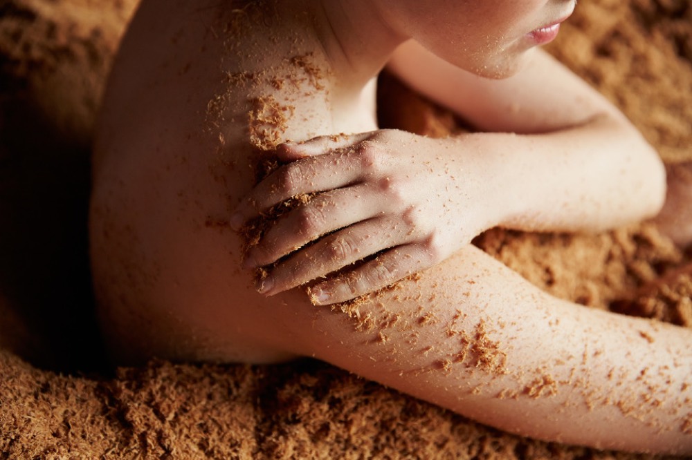 A bather immersed in warm fermenting cedar shavings at the Osmosis cedar enzyme bath
